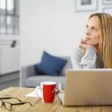 Working female looking distractedly away from her laptop